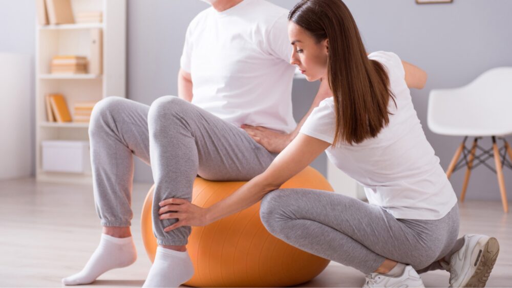 Mann der auf einem Gymnastikball Physiotherapie macht