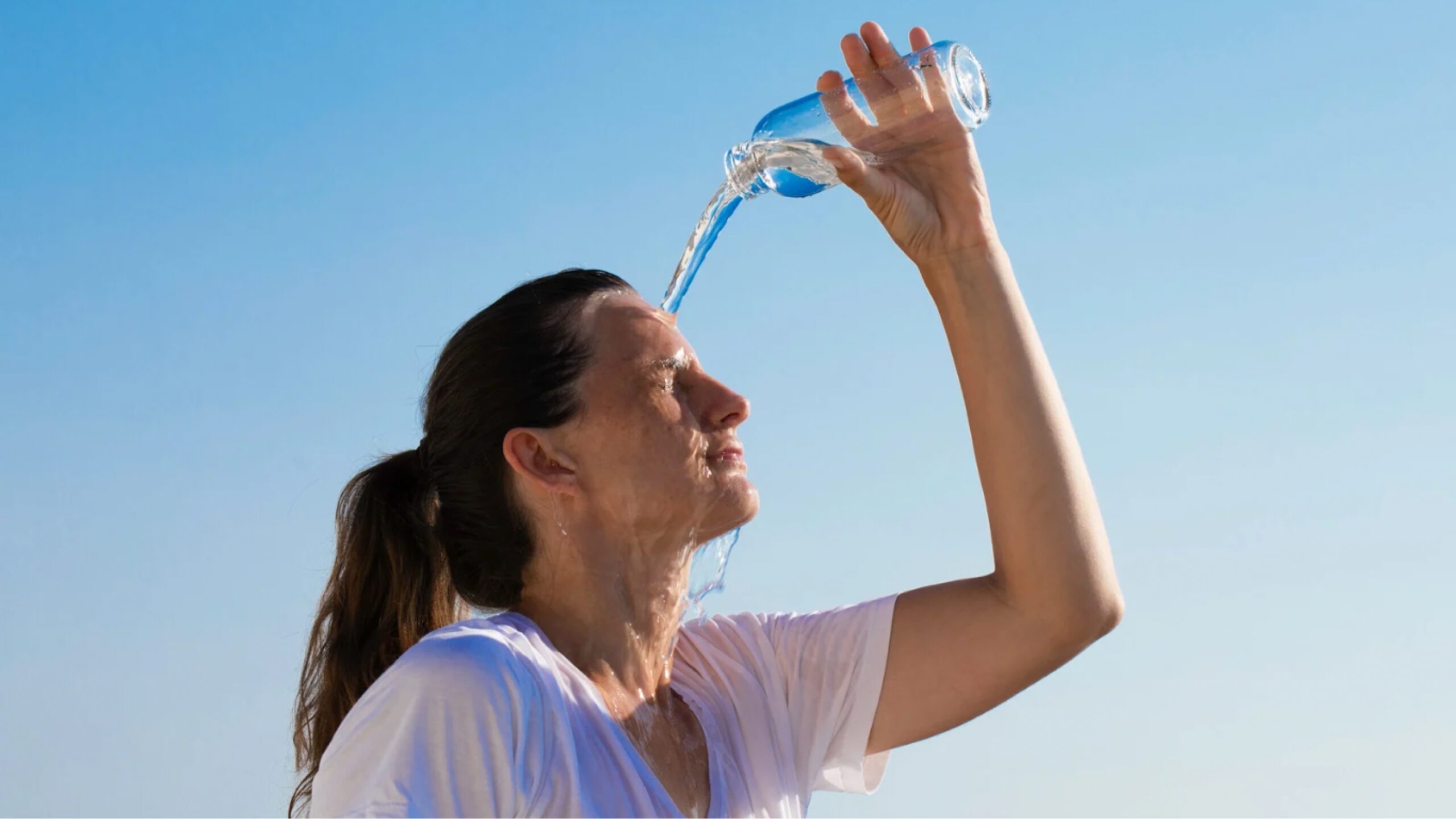 Frau schüttet sich Wasser über Kopf wegen HItze